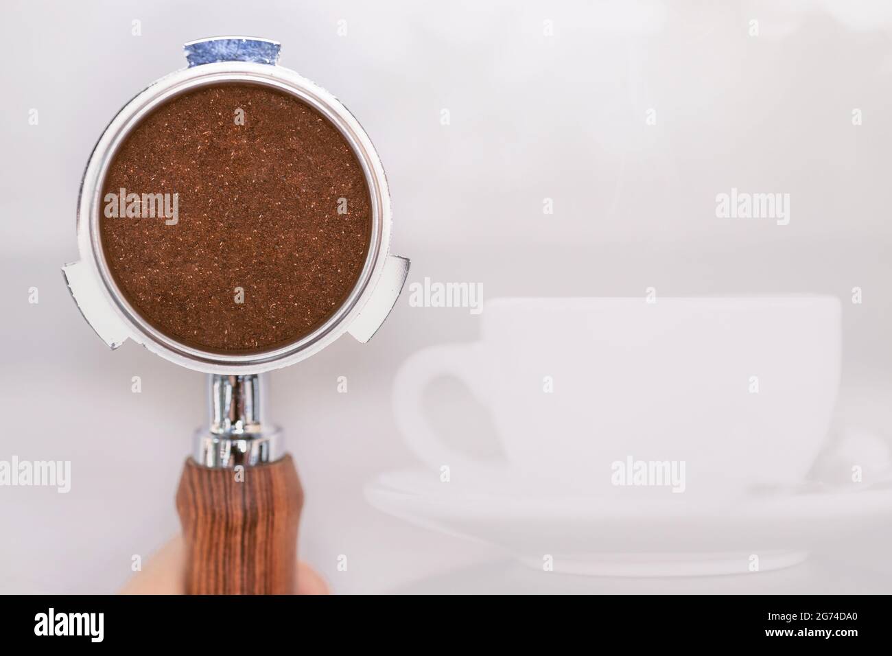 Ground coffee powder in portafilter with space for cafe text and coffee mug background. Stock Photo