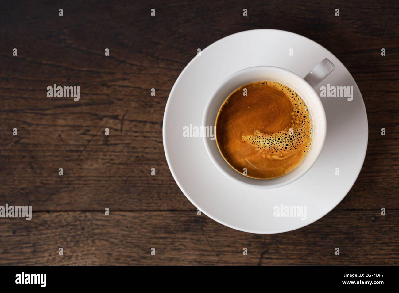 dark rost espresso coffee on white cup on old wooden table background with copy space. Stock Photo