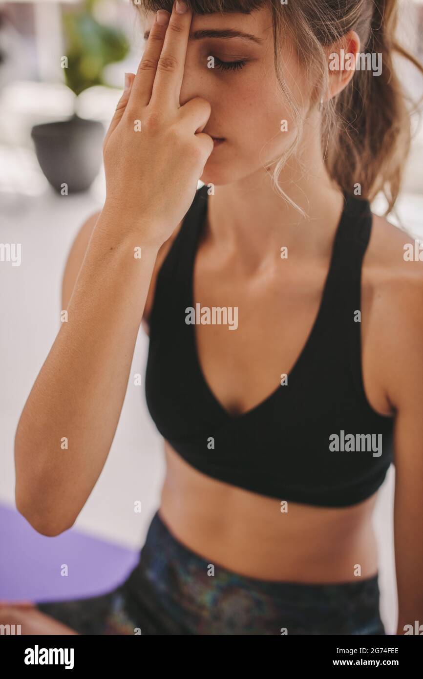 Close up of woman practicing alternate nostril breathing yoga exercise. Young woman doing breathing exercise. Stock Photo