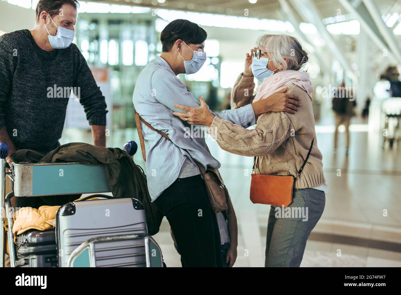 Senior woman talking with her daughter at airport arrival in pandemic. Elderly female meeting her family at airport. Stock Photo