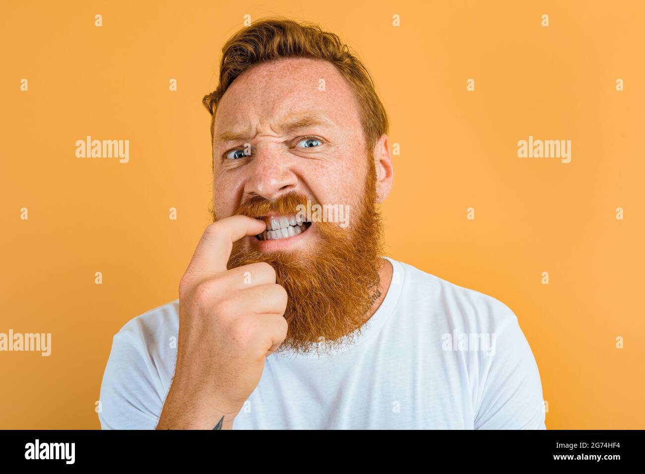 Doubter man with beard, tattoo and white t-shirt Stock Photo