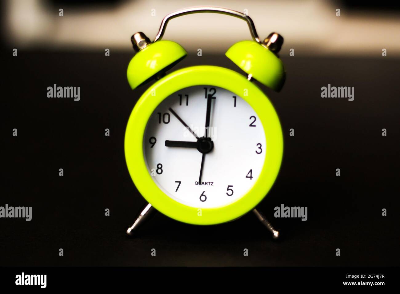 Light green alarm clock on a black background. Back to school. Time