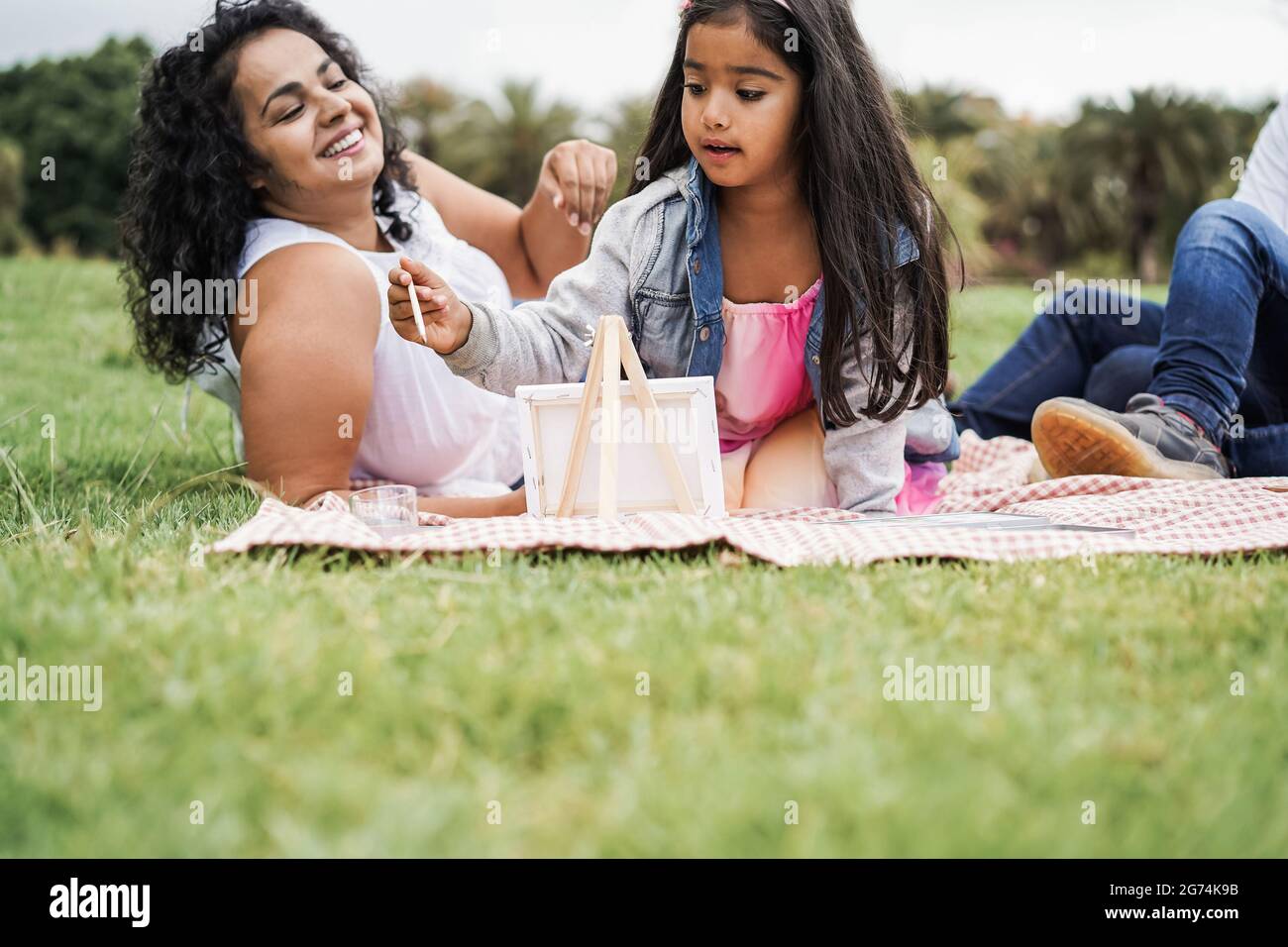 Happy indian family having fun painting with children outdoor at city
