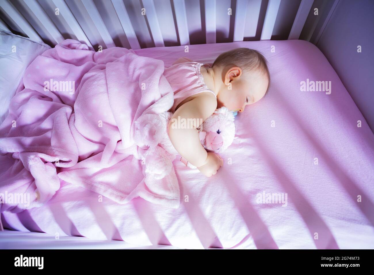 Little baby girl sleep in crib hugging pink bear Stock Photo Alamy