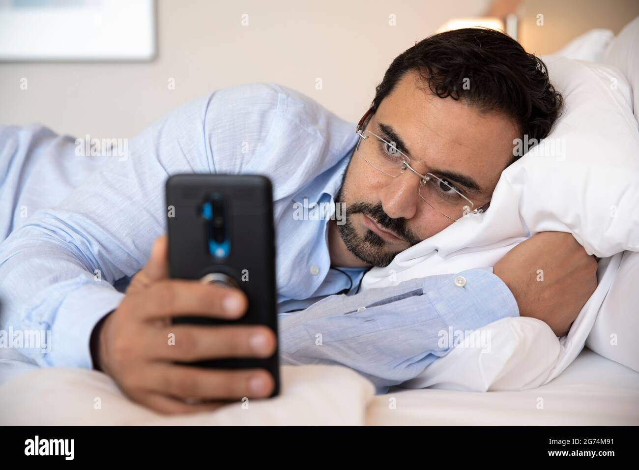 middle aged arab man in bed with his phone Stock Photo