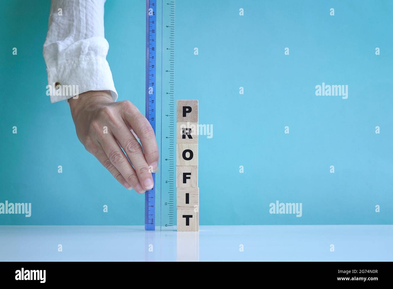 Businesswoman's hand measure profit with a ruler. Blue background with copy space. Stock Photo