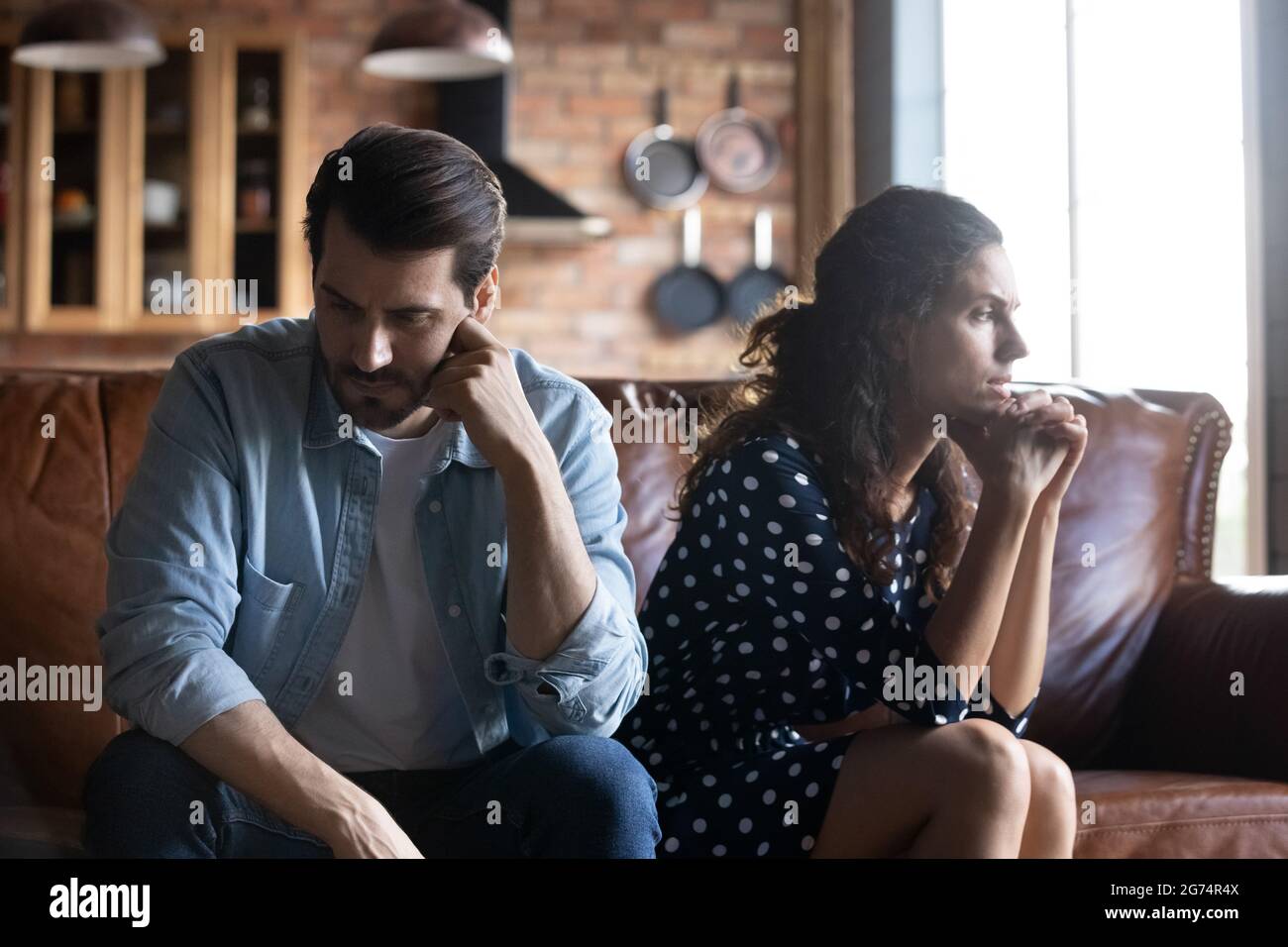 Angry young husband and wife sitting together, hating, ignoring Stock Photo