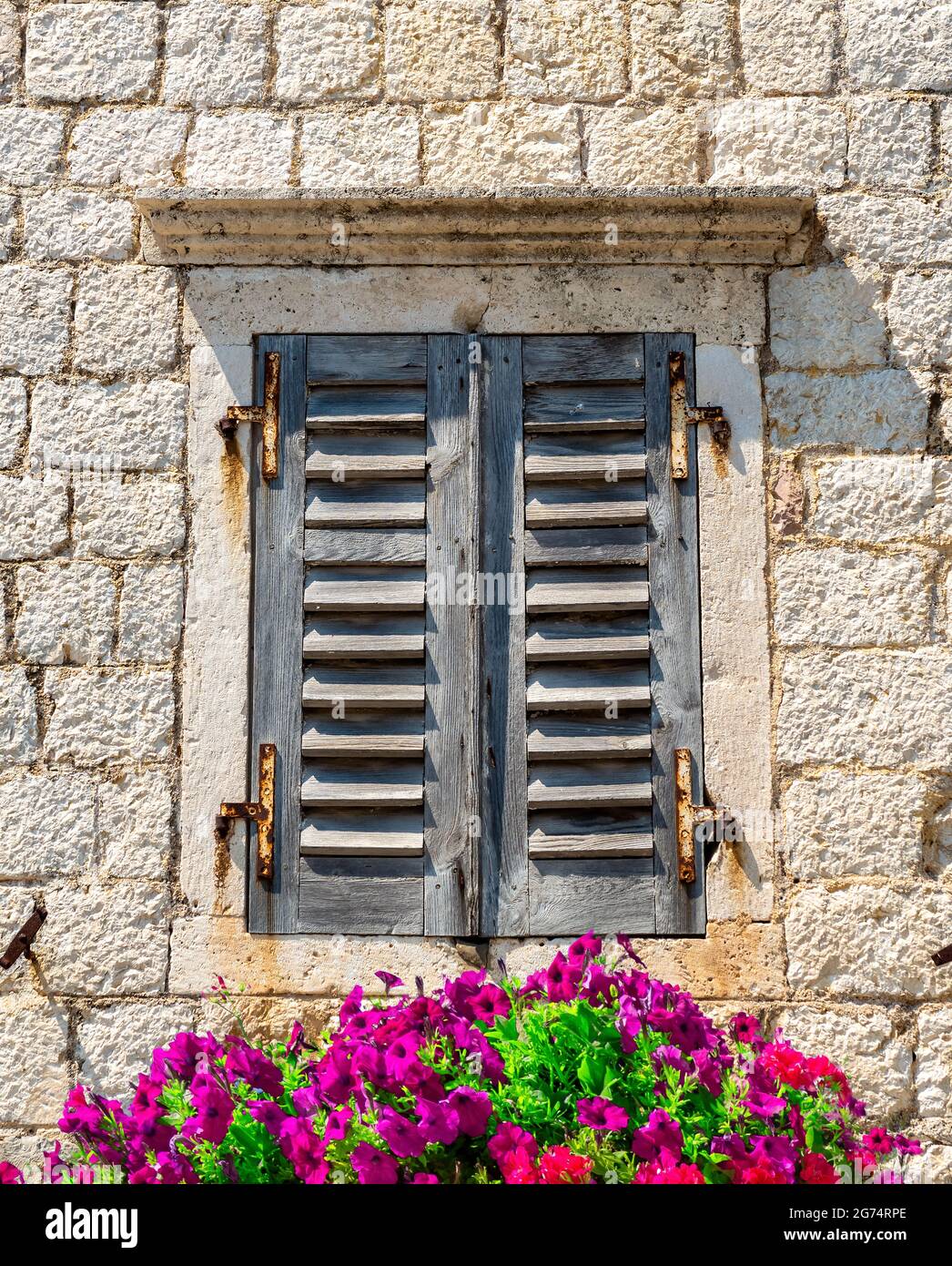 Old window with closed shutters decorated with flowers Stock Photo