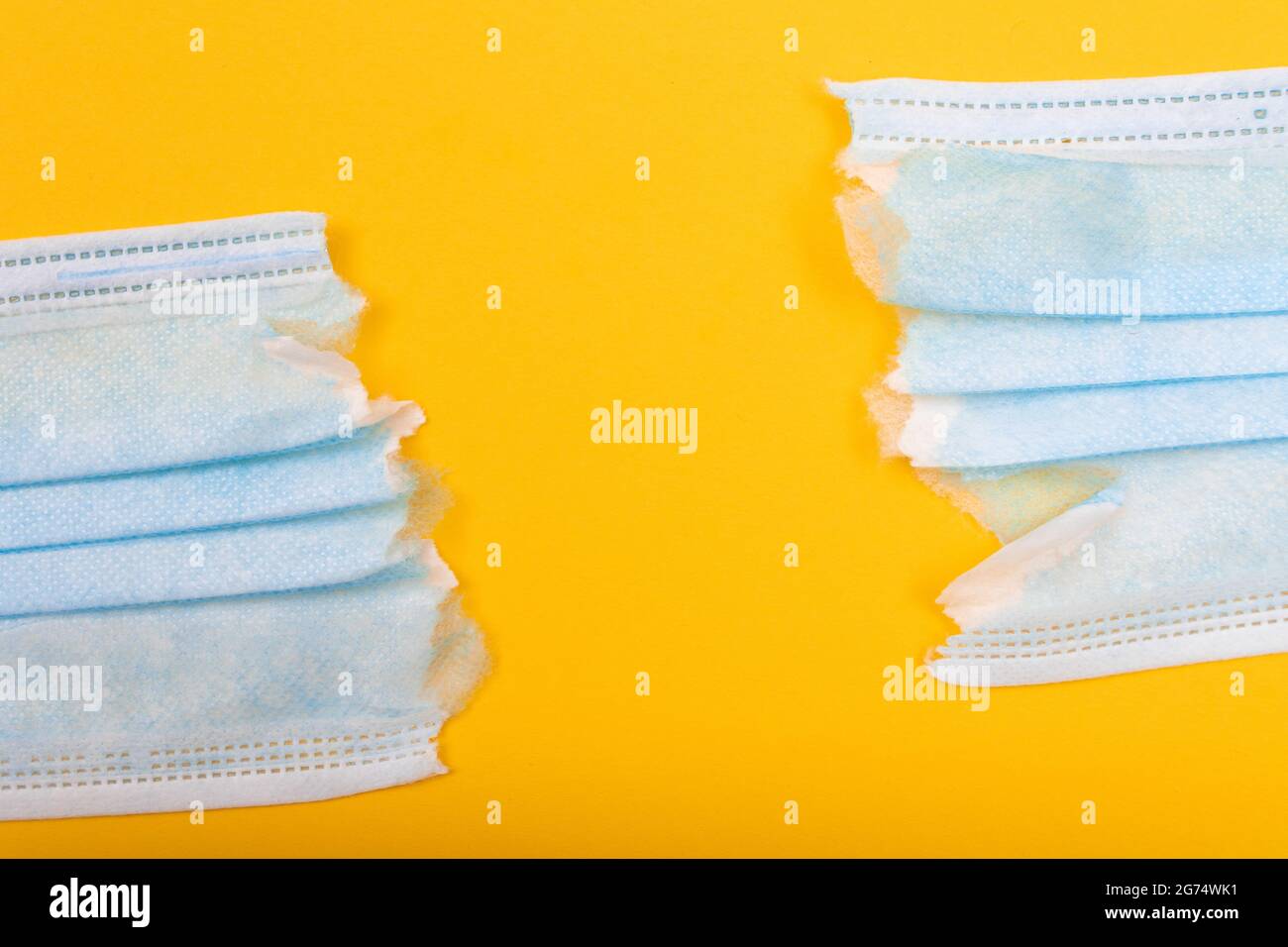 Anti Mask Concept - Torn Medical Face Mask Lying on Yellow Background. Pandemic and Lockdown End - Top View, Flat Lay Stock Photo