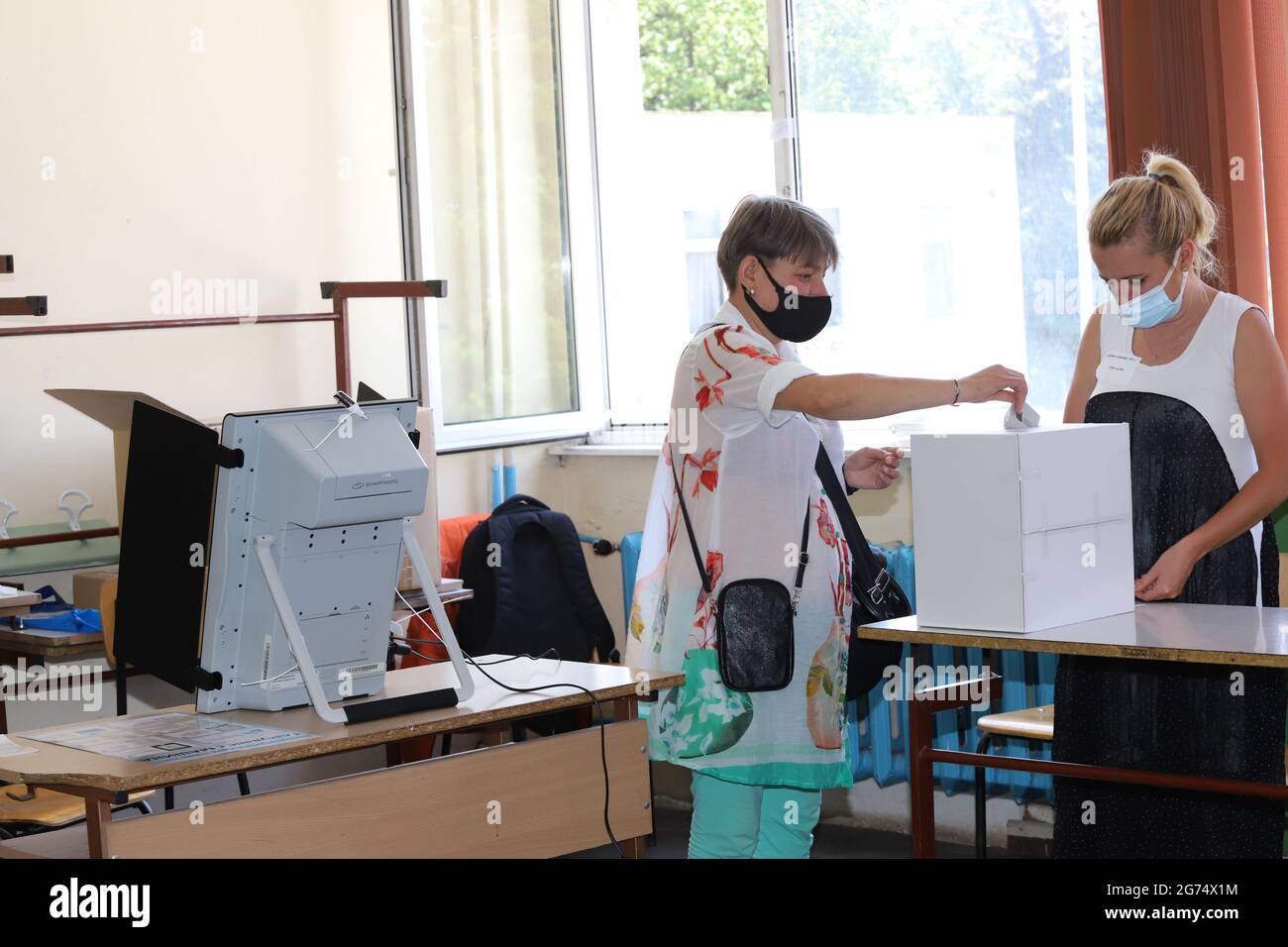 People with masks are using a voting machine in Bulgarian parliamentary elections in Sofia, Bulgaria on July 11, 2021 Stock Photo
