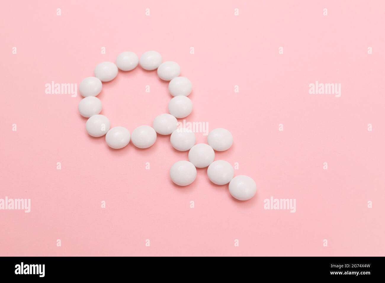 Female Gender Symbol Made from White Pills - Women's Health and Medicine, Medicaments for Women, Lying on Pink Background. Copy Space Stock Photo
