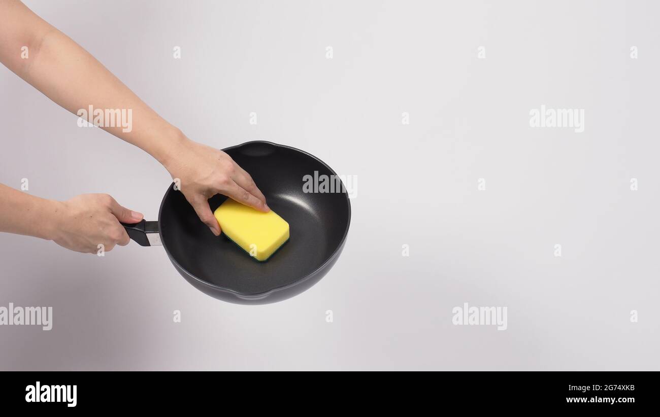 Pan cleaning. Man hand on white background cleaning the non stick pan with  handy dish washing sponge which yellow color on the soft side and green on  Stock Photo - Alamy