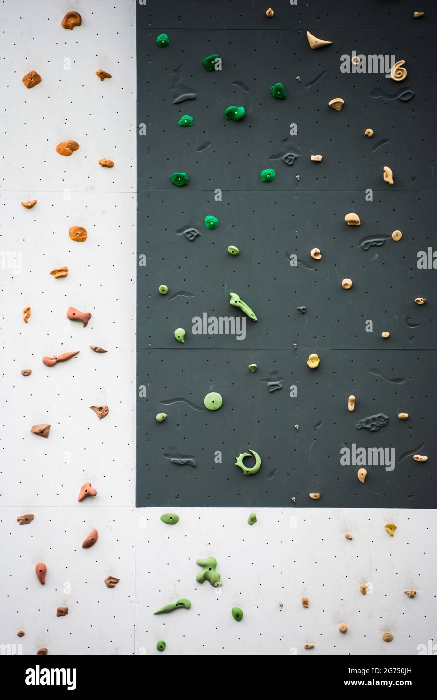 Artificial rock climbing wall showing various colored grips at outdoor gym adventure park. Stock Photo