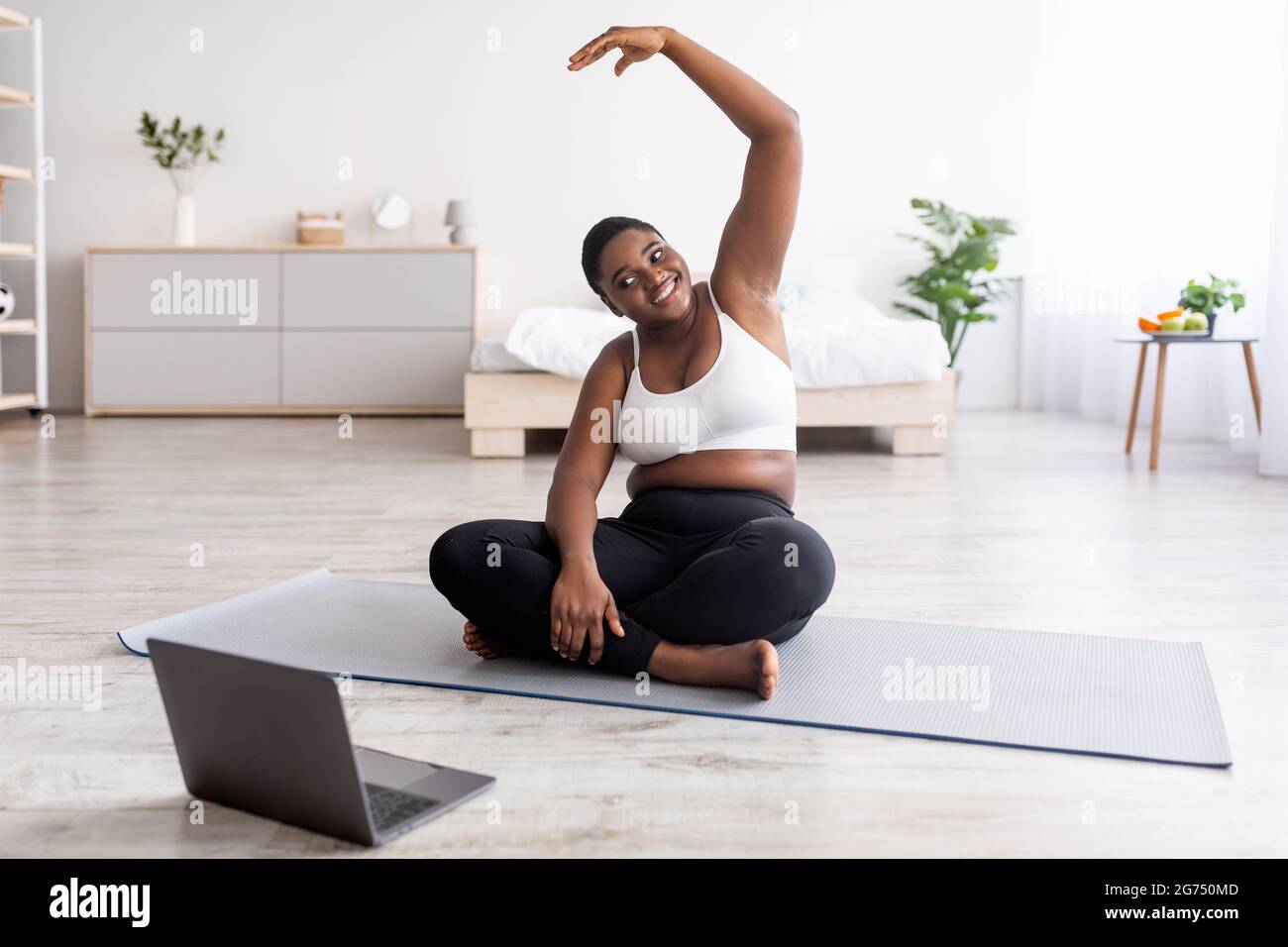 Online weight loss training. Curvy black woman working out stretching near laptop following video tutorial indoors Stock Photo Alamy
