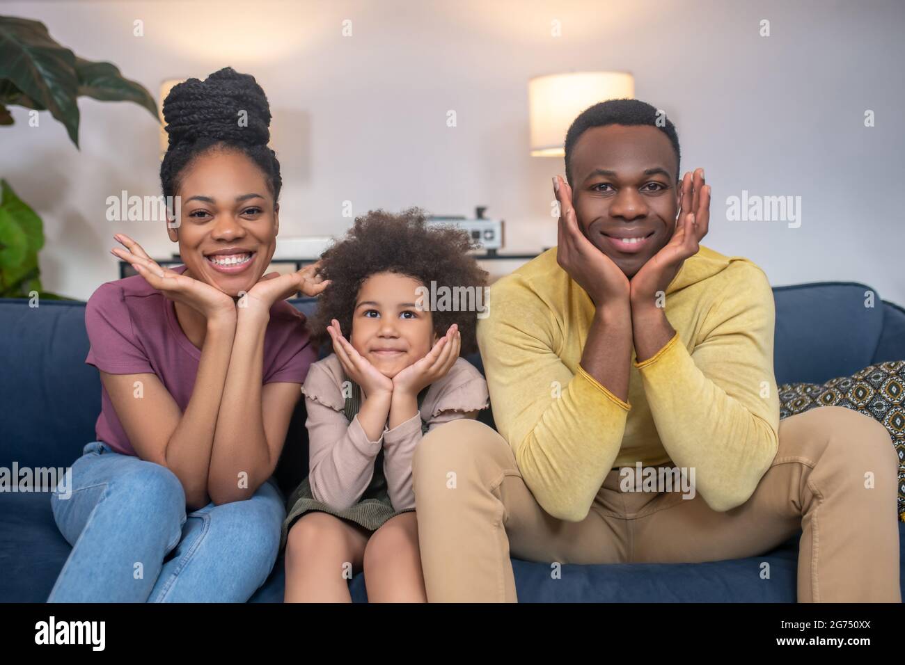 Man woman and little girl cheerful sitting on couch Stock Photo