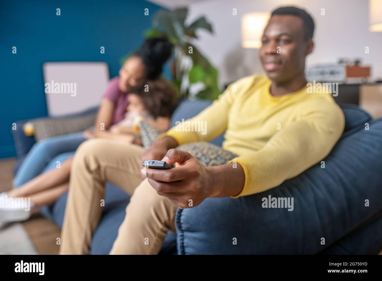 TV remote control in hand of dark-skinned man Stock Photo