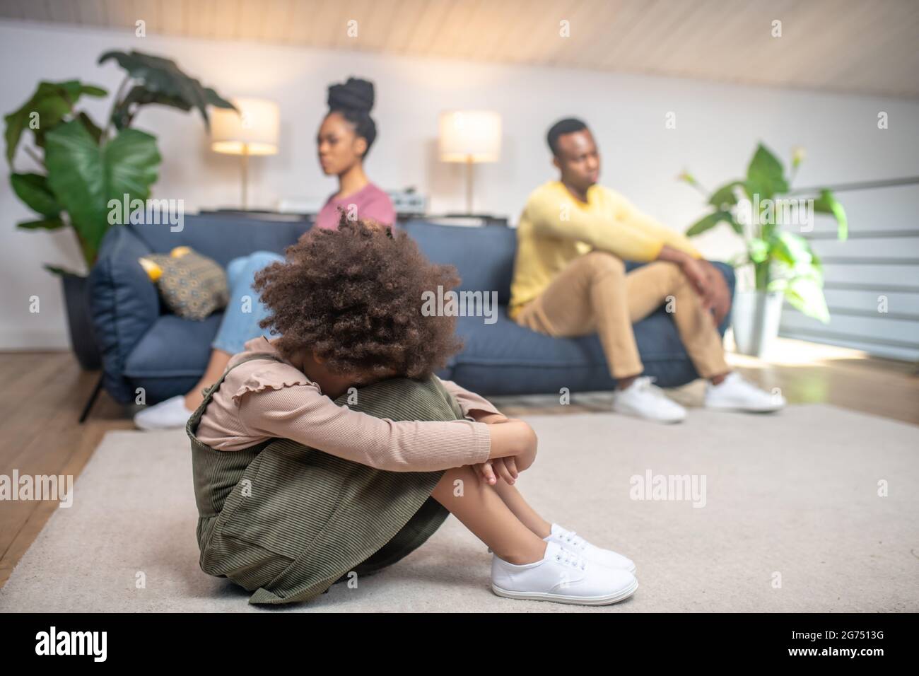Unhappy little girl and sad parents at home Stock Photo