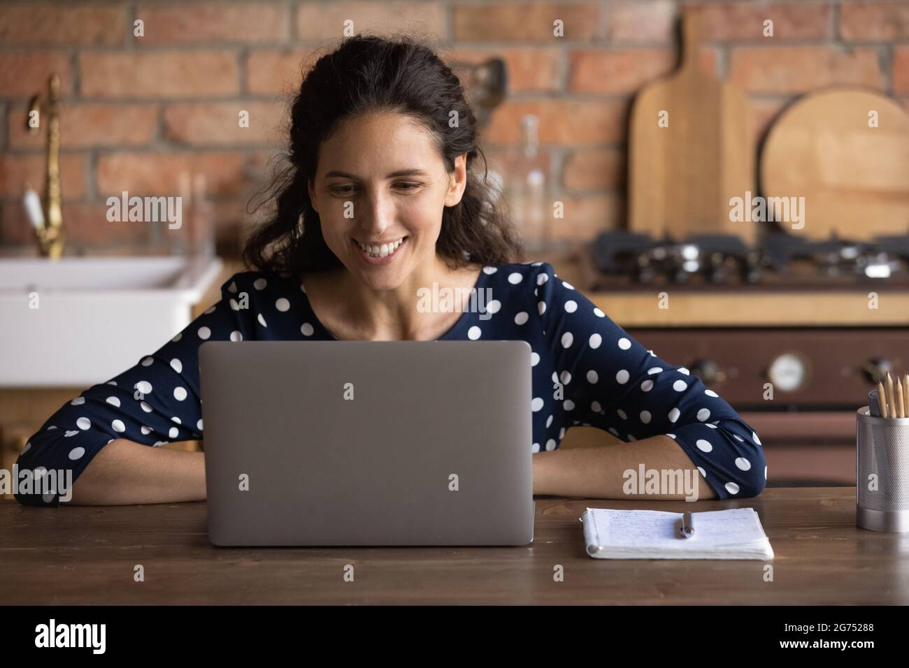 Happy young Hispanic employee working at laptop from home Stock Photo