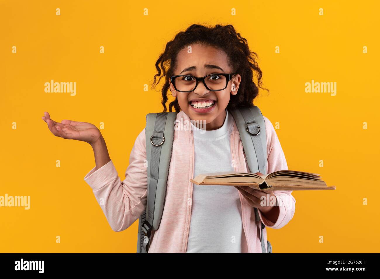 Confused black girl holding open book shrugging shoulders Stock Photo