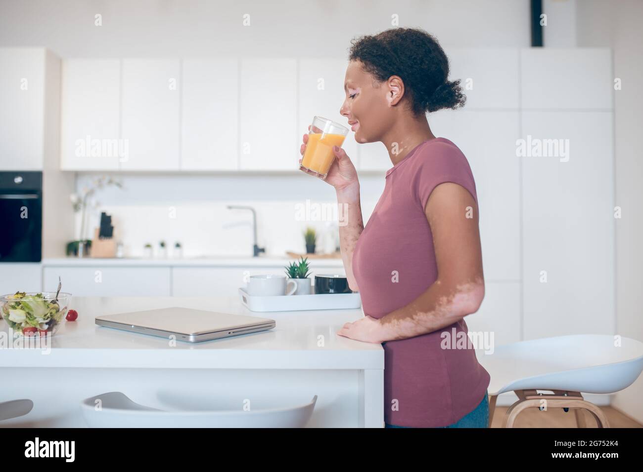A dark-skinned woman drinking an orange juice Stock Photo