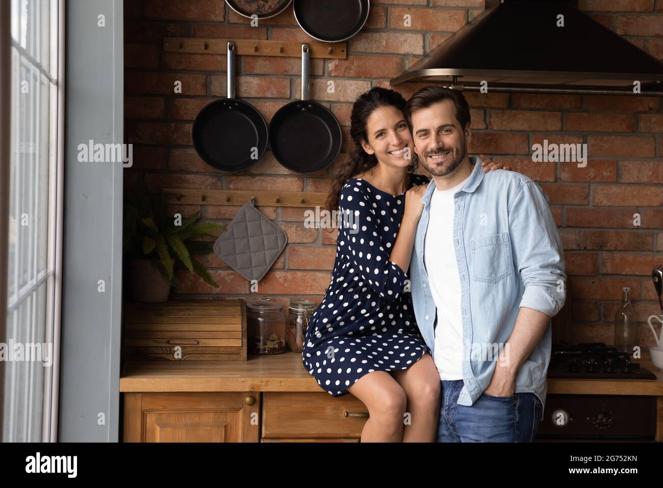 Happy young married couple hugging in kitchen, looking at camera Stock Photo