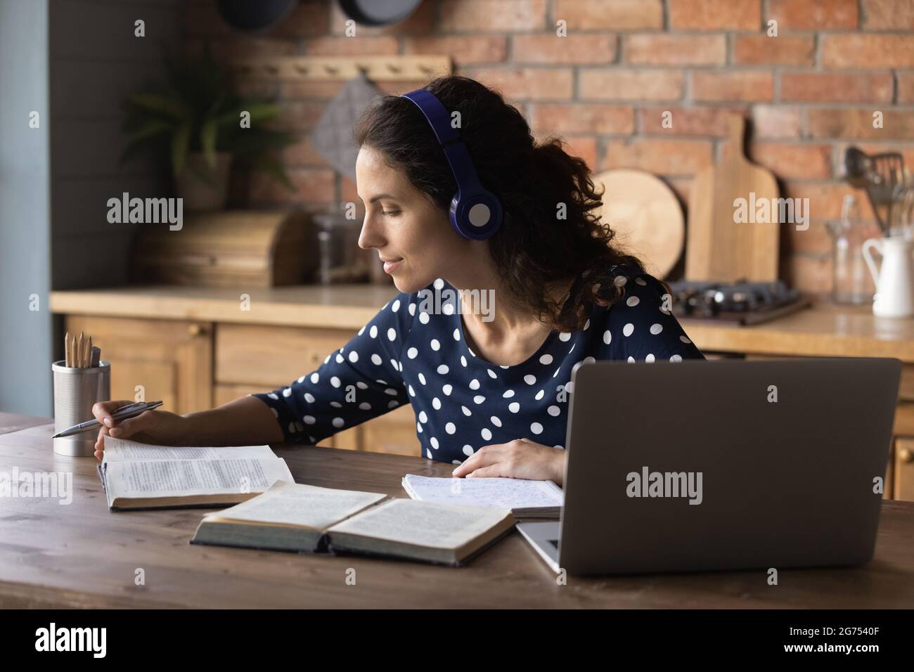 Focused student woman using headphones and laptop Stock Photo