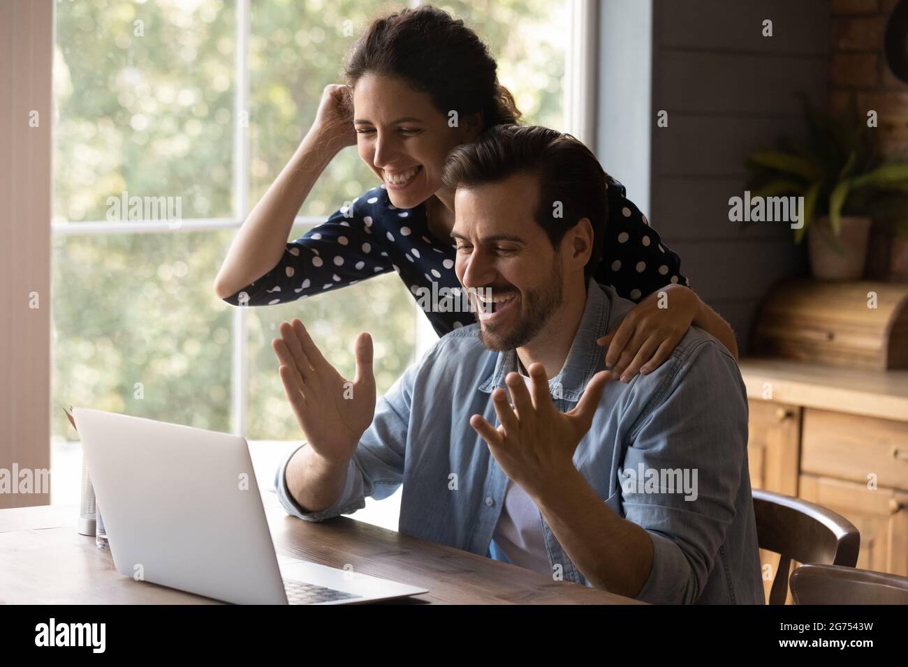 Overjoyed millennial couple using laptop, looking at screen Stock Photo
