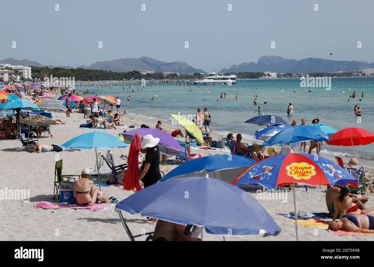 Maorca, Spain. 11th July, 2021. Under colorful umbrellas, many people enjoy the sun, sand and sea on the beach of Playa de Muro in the north of Mallorca. The federal government has declared all of Spain with Mallorca and the Canary Islands in view of rapidly increasing Corona numbers to the risk area. The practical effects for Mallorca holidaymakers are limited for the time being. Credit: Clara Margais/dpa/Alamy Live News Stock Photo