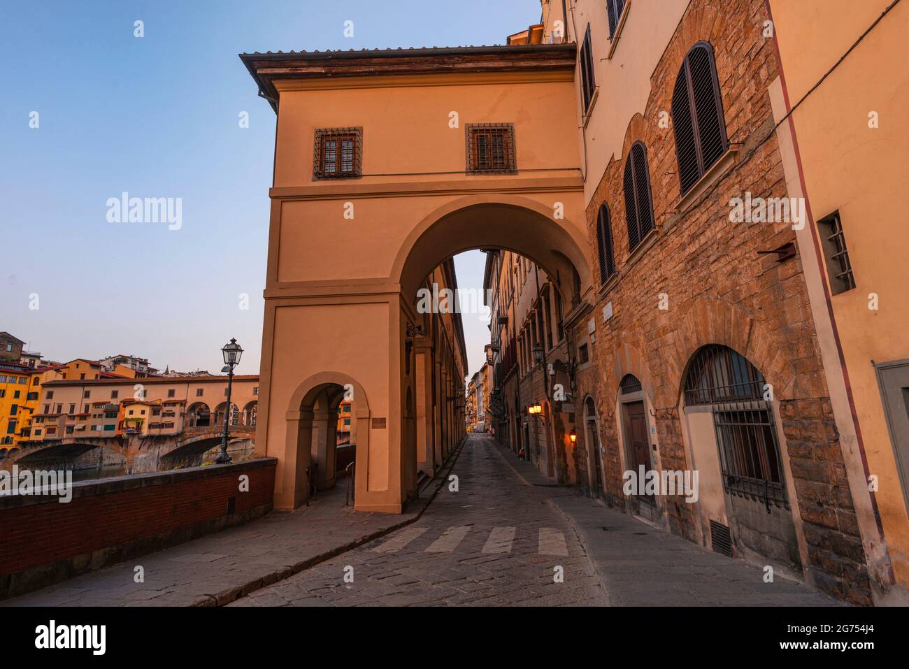 Corridoio Vasariano Passage, Florence, Italy. Beautiful symmetrical, warm yellow architecture. Vasari Corridor. Ponte Vecchio in the background Stock Photo