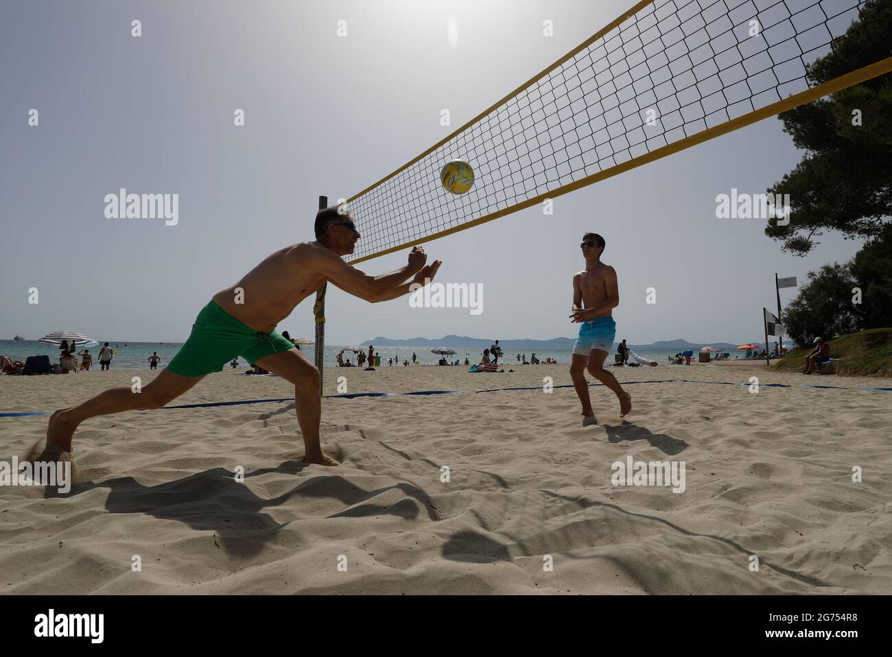 Spain. 11th July, 2021. The tourists Birger (l) and Olli from Rostock play volleyball on the beach of Playa de Muro in the north of Mallorca. The federal government has declared all of Spain with Mallorca and the Canary Islands in view of rapidly increasing Corona numbers to the risk area. The practical effects for Mallorca holidaymakers are limited for the time being. Credit: Clara Margais/dpa/Alamy Live News Stock Photo