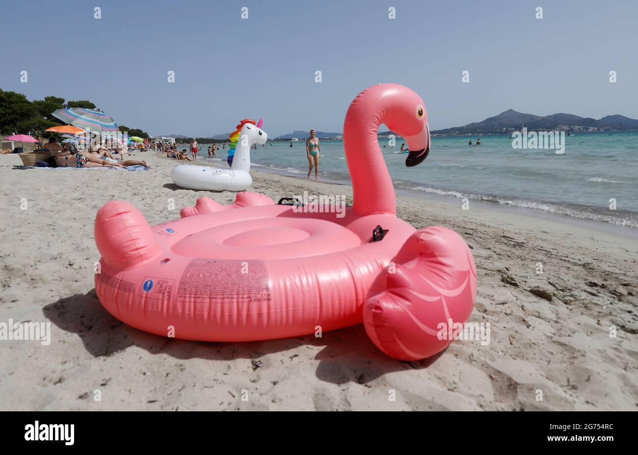 Spain. 11th July, 2021. An inflatable pink flamingo lies on the beach of Playa de Muro in the north of Mallorca. The federal government has declared all of Spain with Mallorca and the Canary Islands in view of rapidly increasing Corona numbers to the risk area. The practical effects for Mallorca holidaymakers are limited for the time being. Credit: Clara Margais/dpa/Alamy Live News Stock Photo