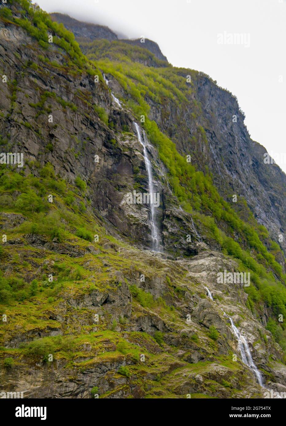 Small scanty waterfall on the side of the mountain. Scenic view of a waterfall while cruising the fjord in Norway. Stock Photo