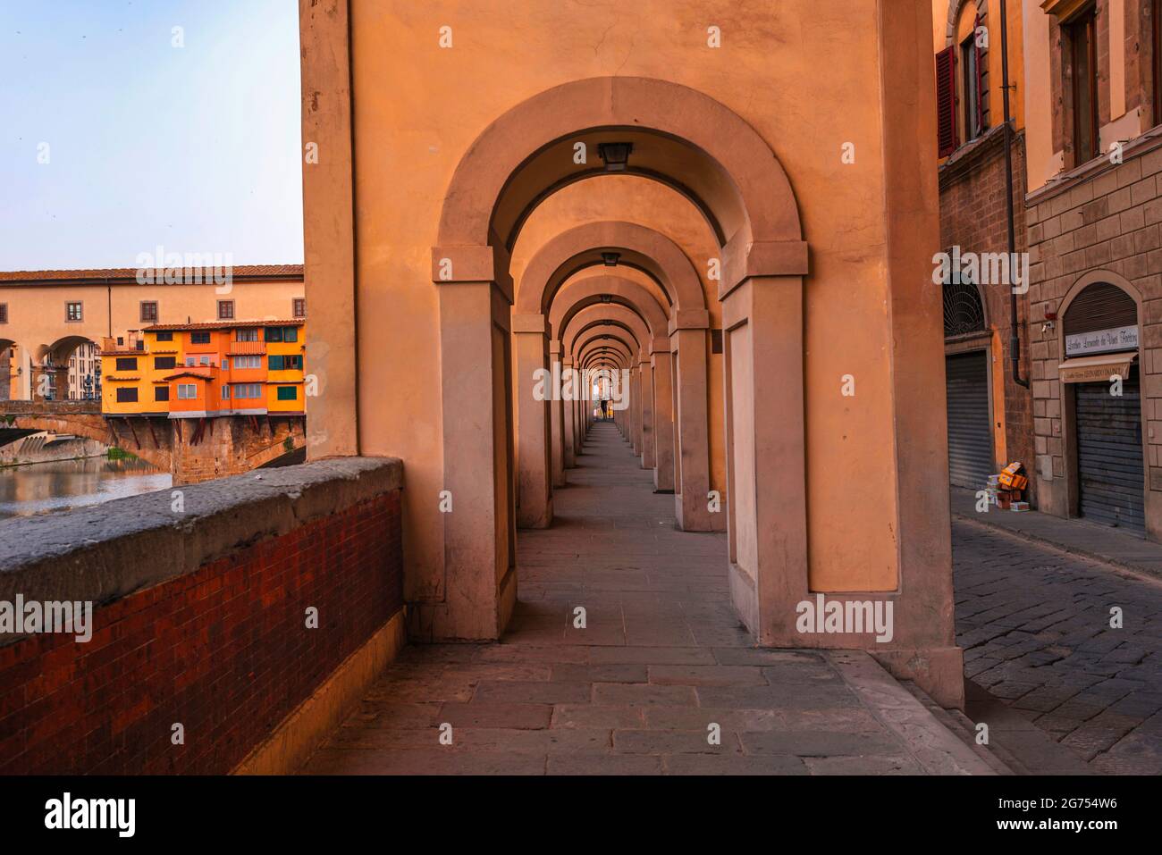 Corridoio Vasariano Passage, Florence, Italy. Beautiful symmetrical, warm yellow architecture. Vasari Corridor. Ponte Vecchio in the background Stock Photo