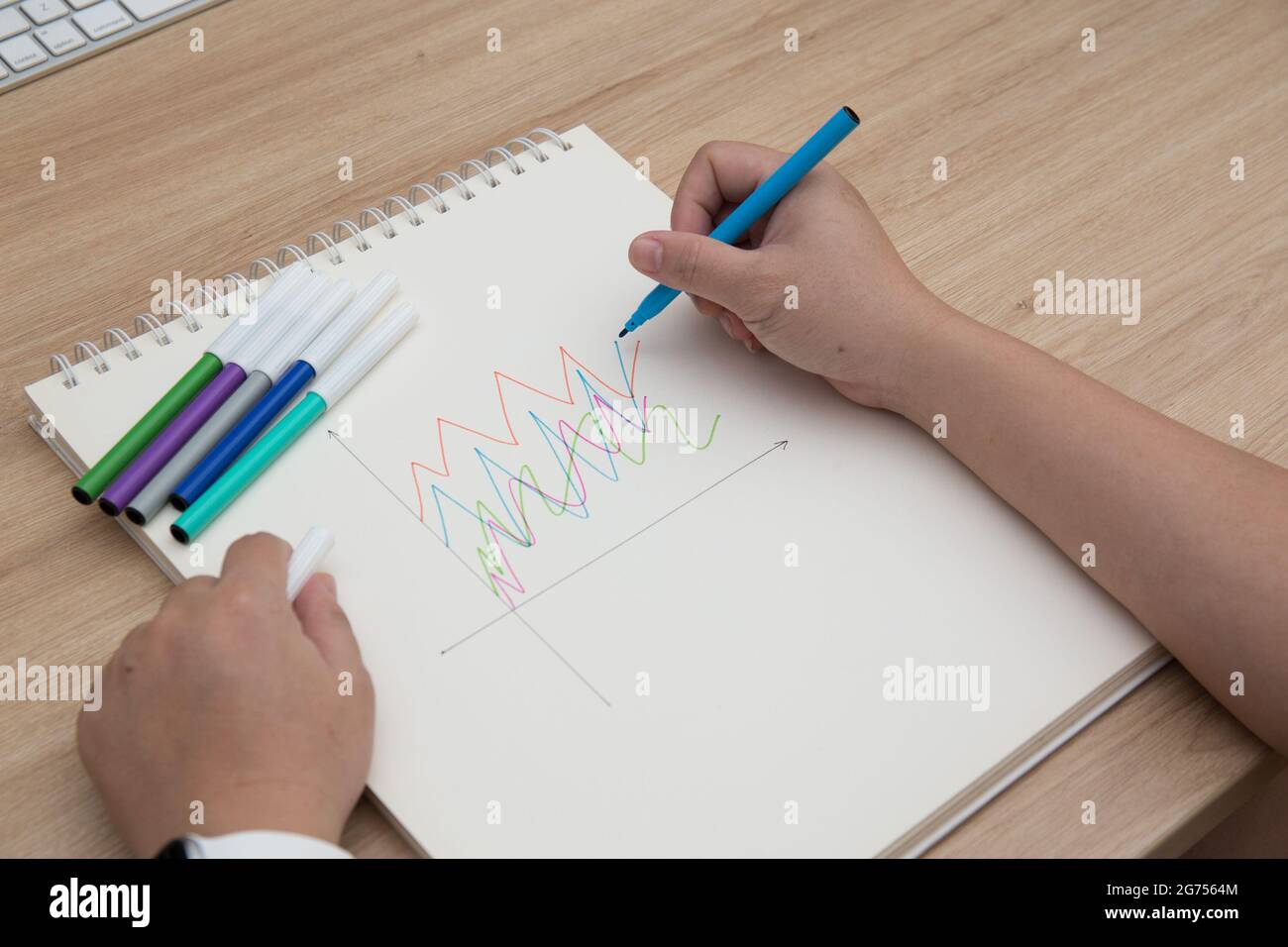A high angle shot of female hands drawing with colorful pens in a ...