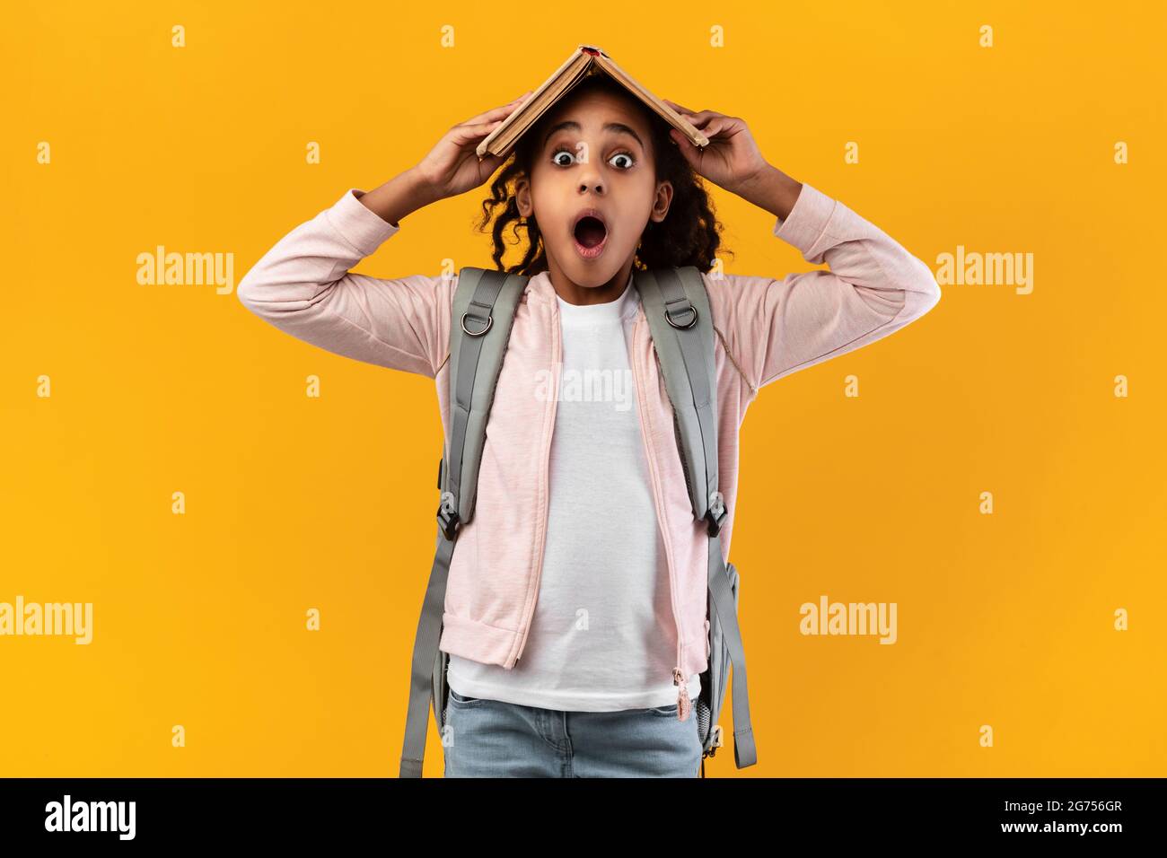 Funny black girl holding open book on her head Stock Photo - Alamy