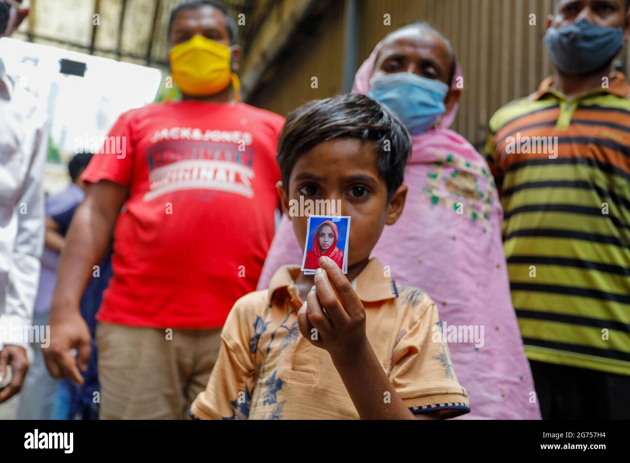 A child holding his mother's photo at the Dhaka Medical College