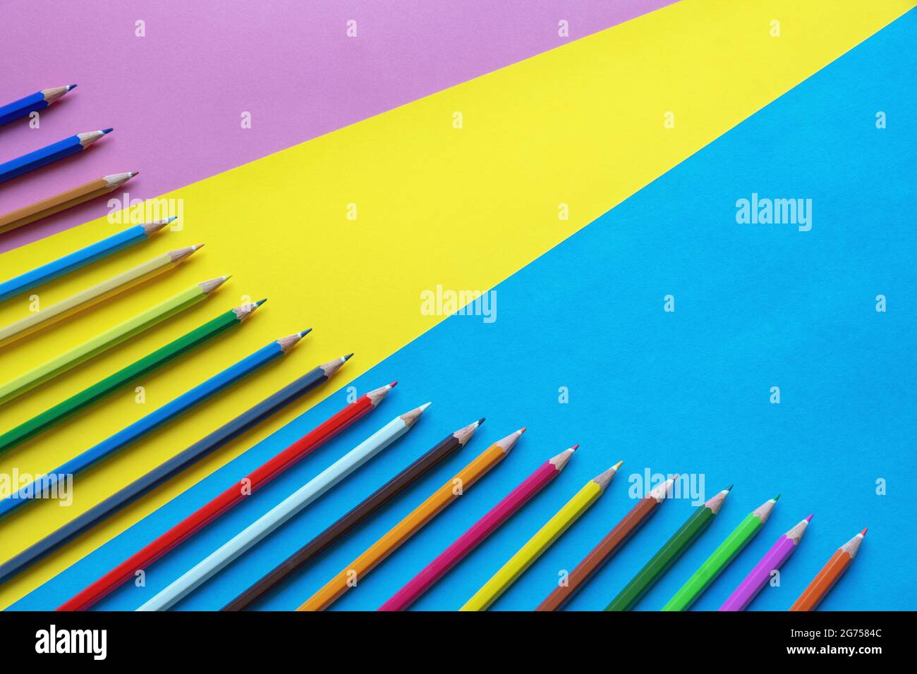 Colorful colored pencils on multicolored paper background. Free space for text Stock Photo