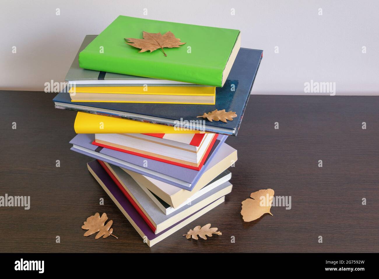 School concept. Stack of  different books and autumn leaves on table. Copy space Stock Photo