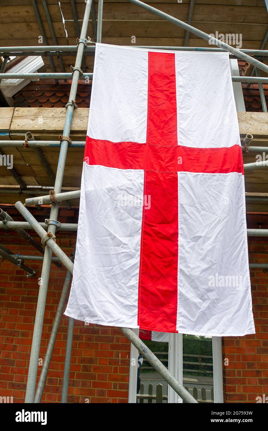 Windsor, Berkshire, UK. 11th July, 2021. A large England flag hangs off scaffolding on a building in Windsor ahead of tonight's match between England v Italy. Credit: Maureen McLean/Alamy Live News Stock Photo