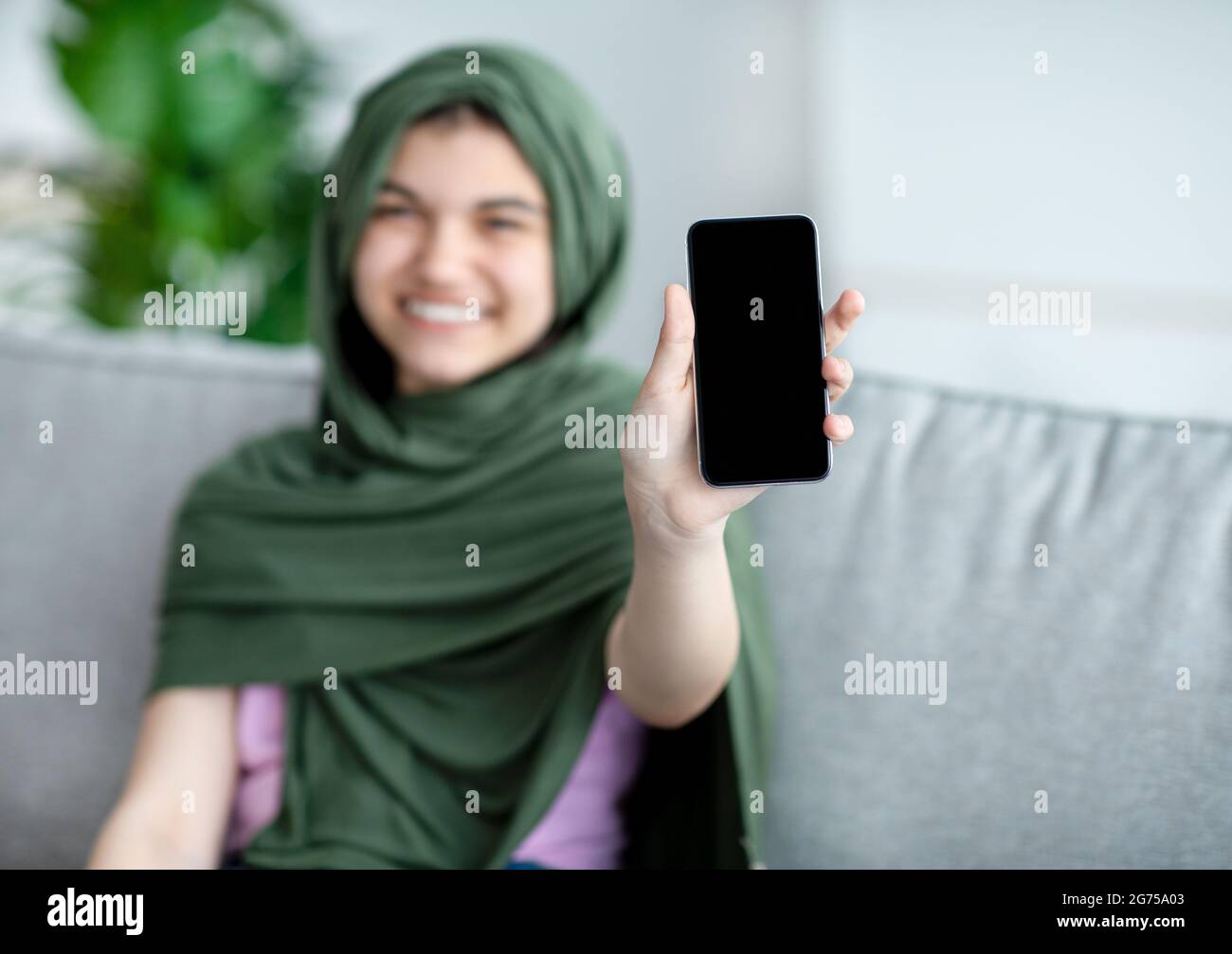 Download Muslim Teenage Girl In Hijab Showing Cellphone With Blank Screen At Home Mockup For Mobile App Or Website Design Stock Photo Alamy