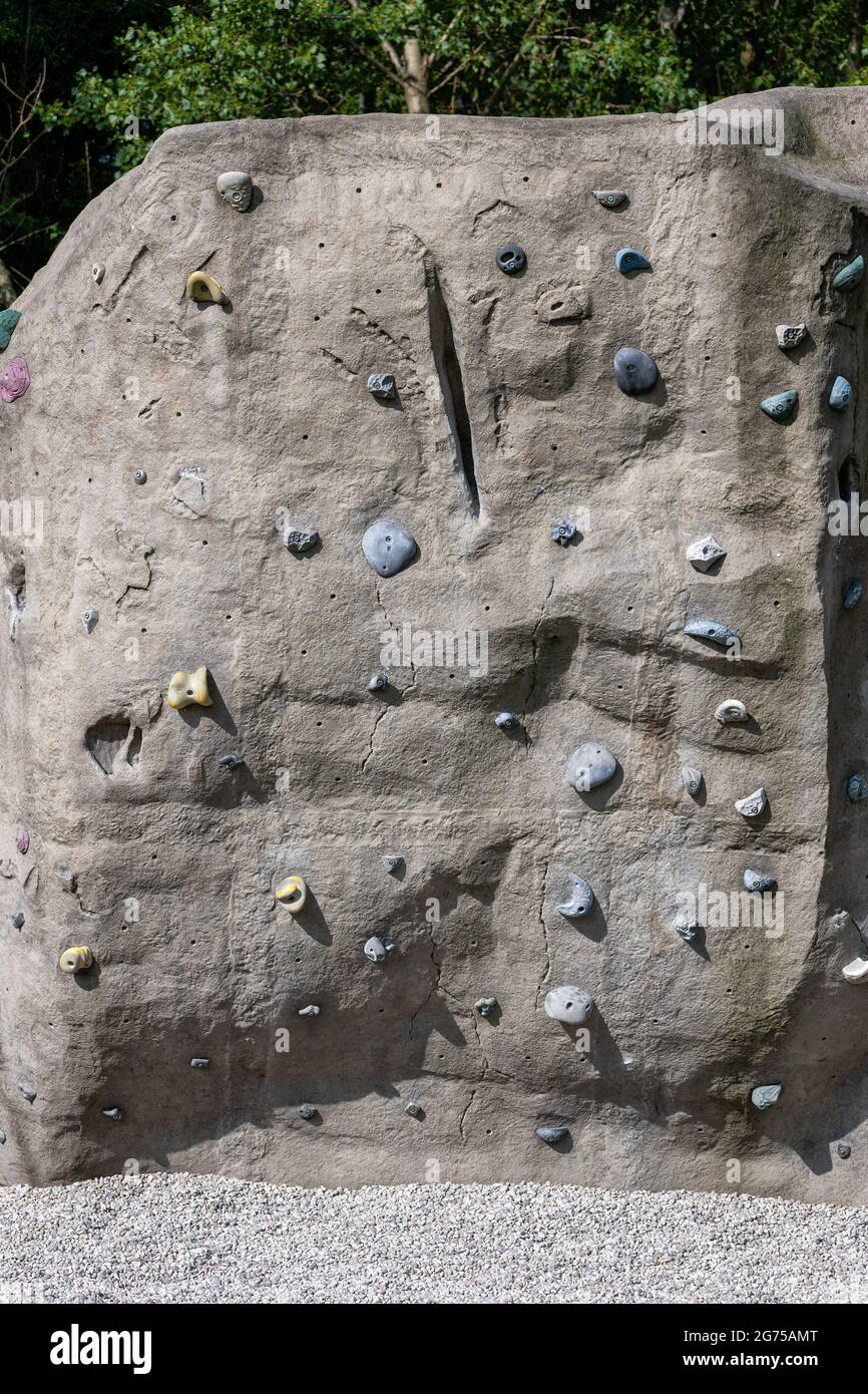 Public climbing wall in urban park, manmade rock with holds and grips for hands and feet. Stock Photo
