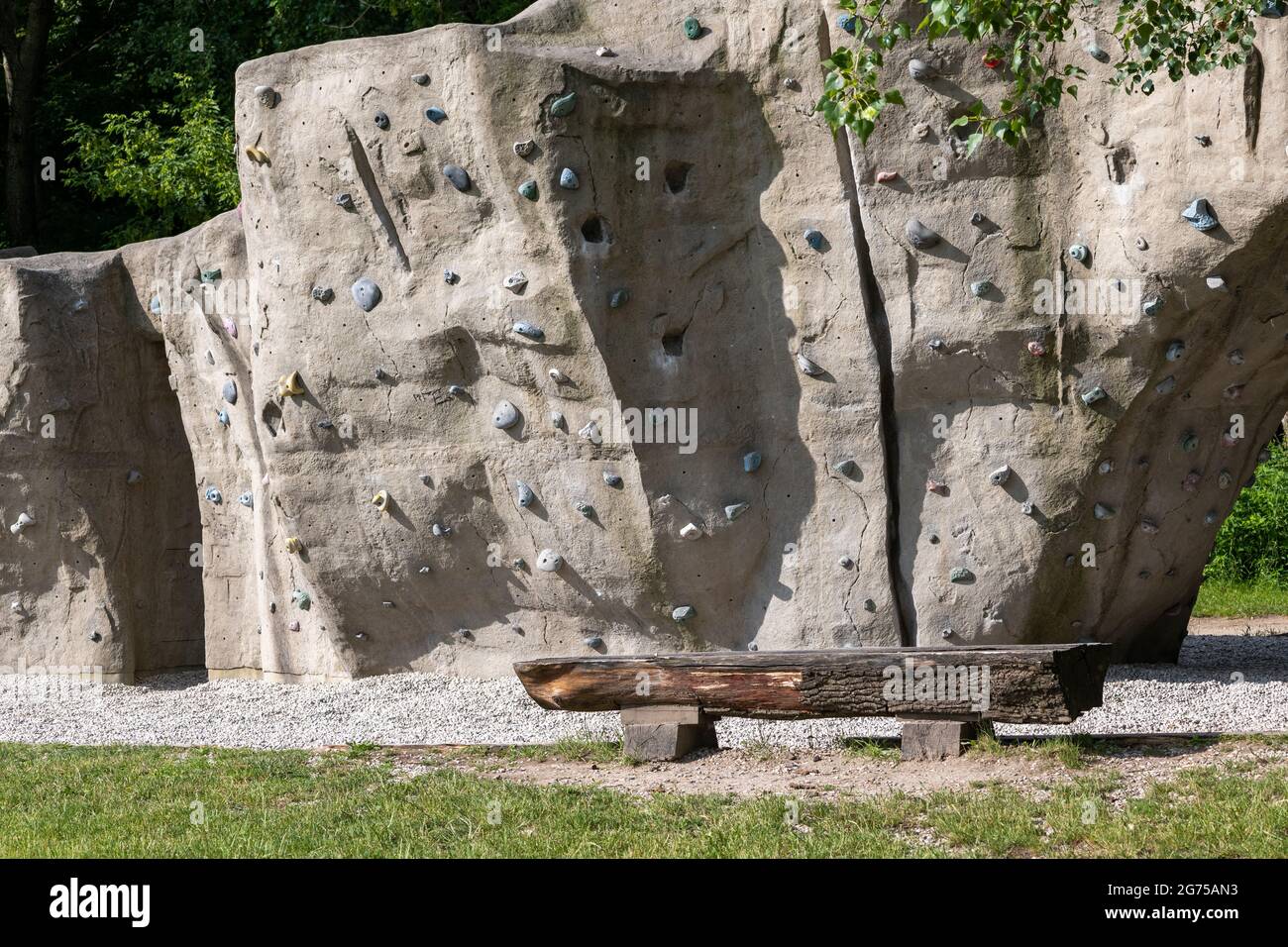 Public climbing wall in urban park, manmade rock with holds and grips for hands and feet. Stock Photo