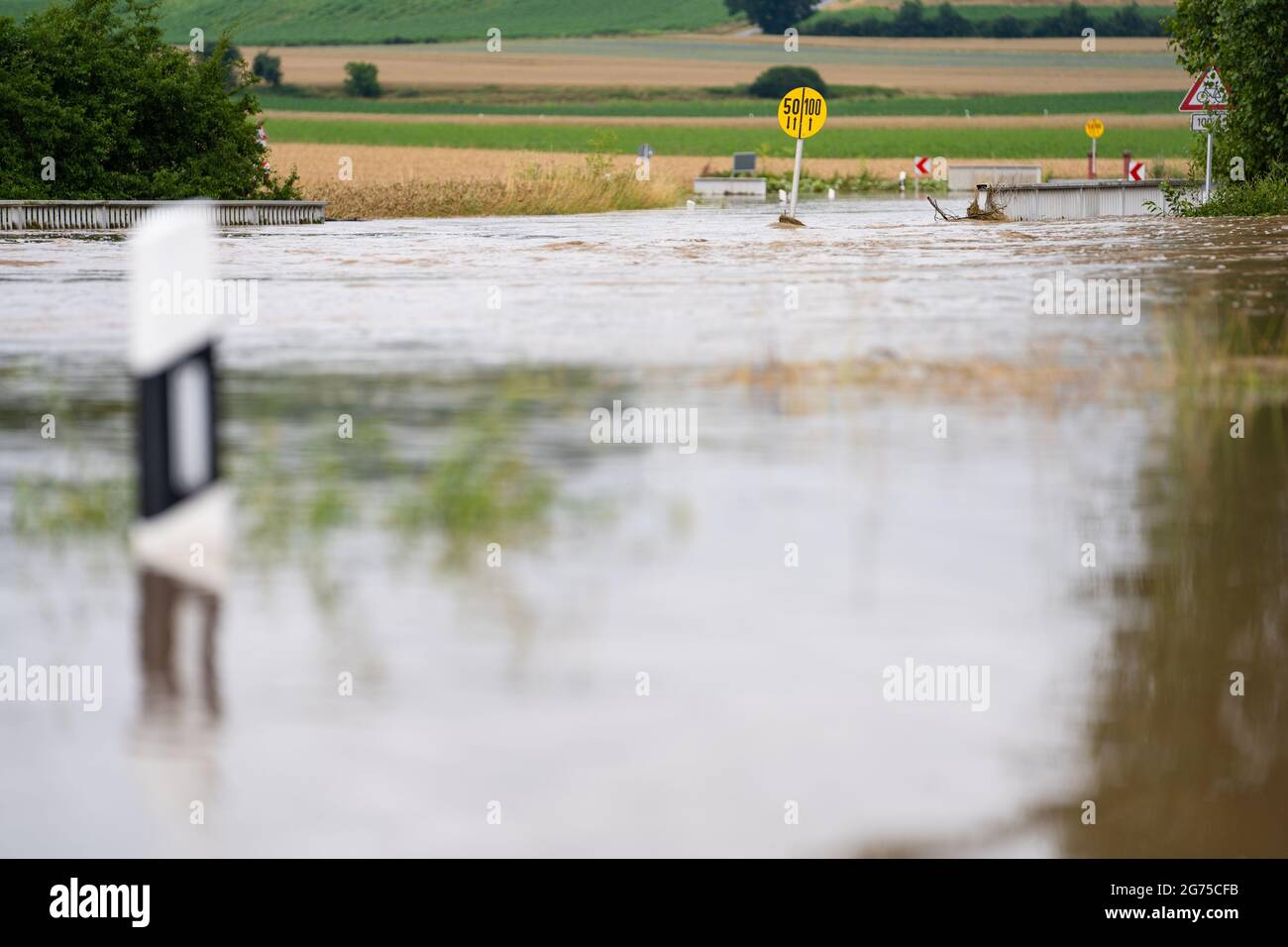 Willersdorf, Germany. 11th July, 2021. The Aisch, which has overflowed its banks, has flooded a country road. Parts of Franconia are still under water due to yesterday's high water. Credit: Nicolas Armer/dpa/Alamy Live News Stock Photo