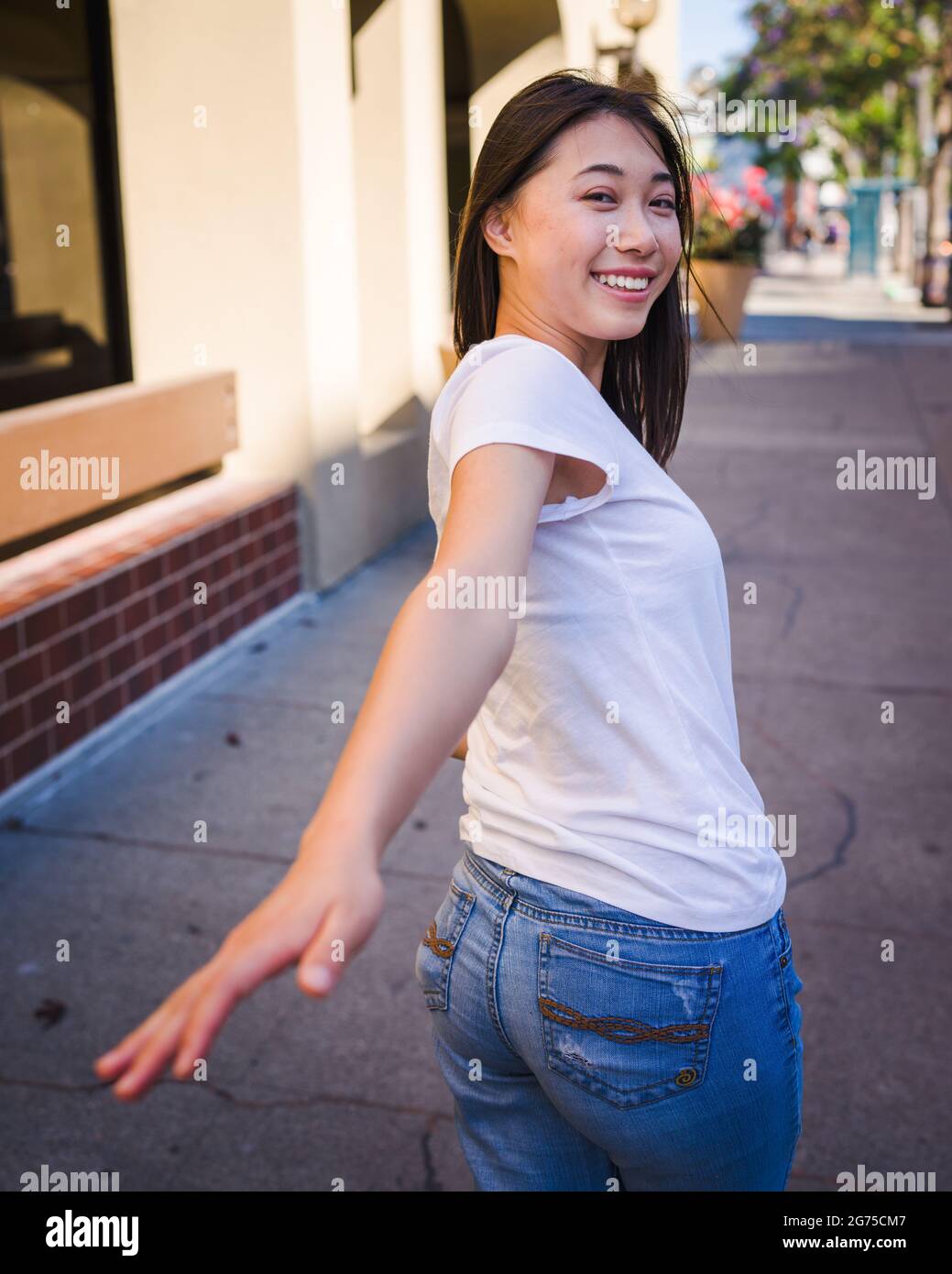 Togetherness, Happy Young Asian Woman Reaching Back to Take Your Hand Stock Photo