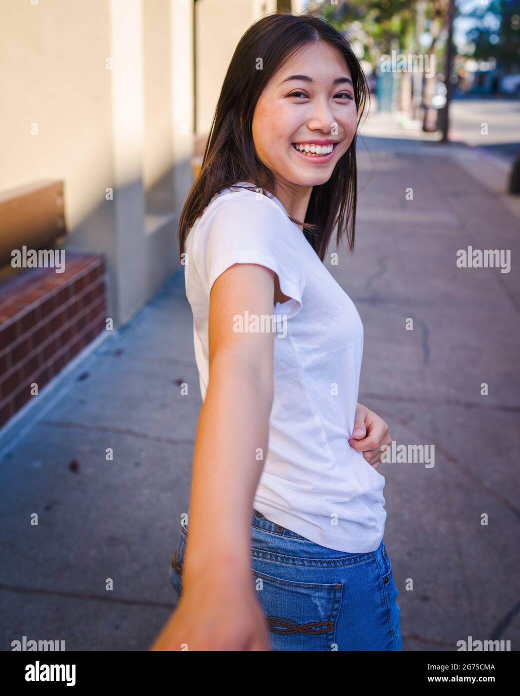 Togetherness, Happy Young Asian Woman Reaching Back to Take Your Hand Stock Photo