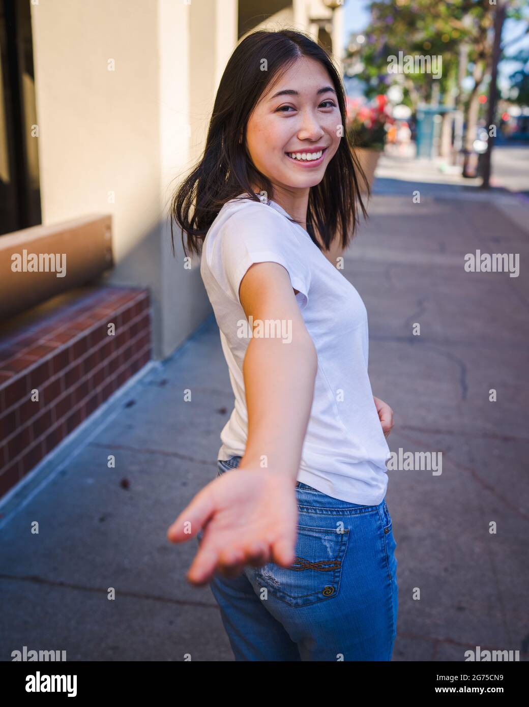 Togetherness, Happy Young Asian Woman Reaching Back to Take Your Hand Stock Photo