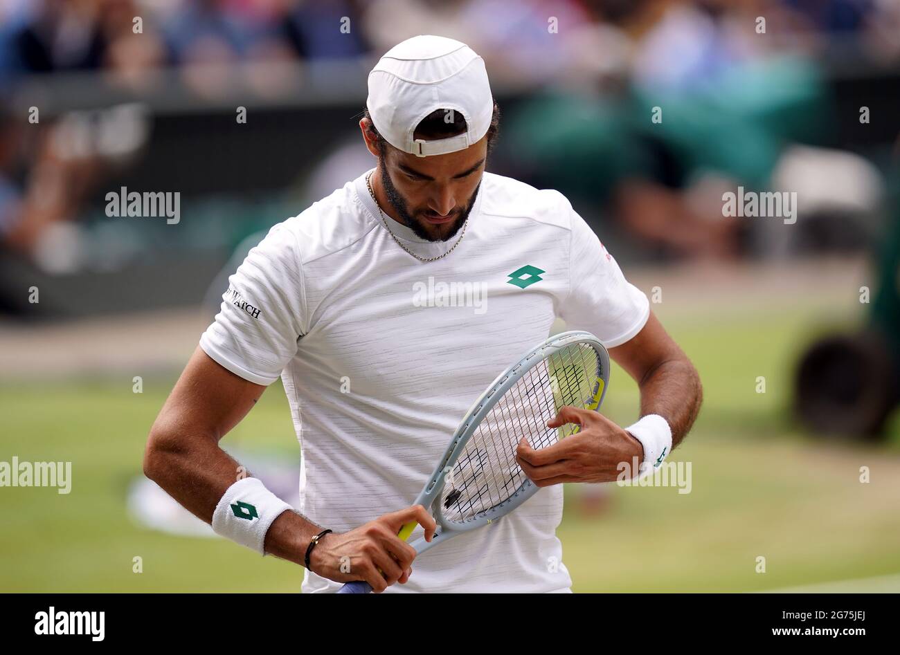 Matteo Berrettini adjusts the strings on his racquet during the Gentlemen's  Singles final against Novak Djokovic on day thirteen of Wimbledon at The  All England Lawn Tennis and Croquet Club, Wimbledon. Picture