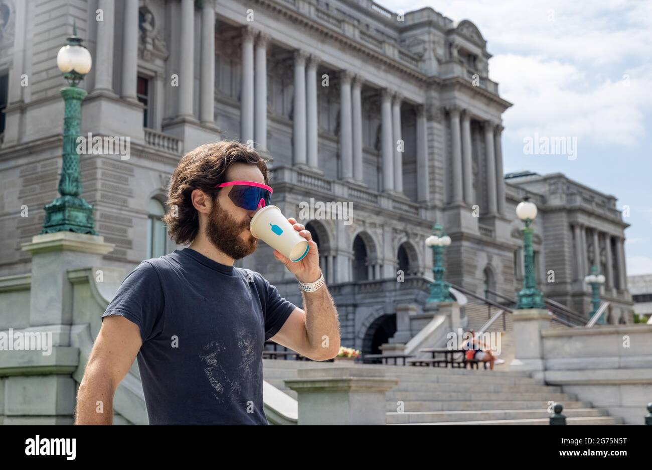 Hipster Man Drinking Blue Bottle Coffee in front of Library of Congress in Washington DC Stock Photo