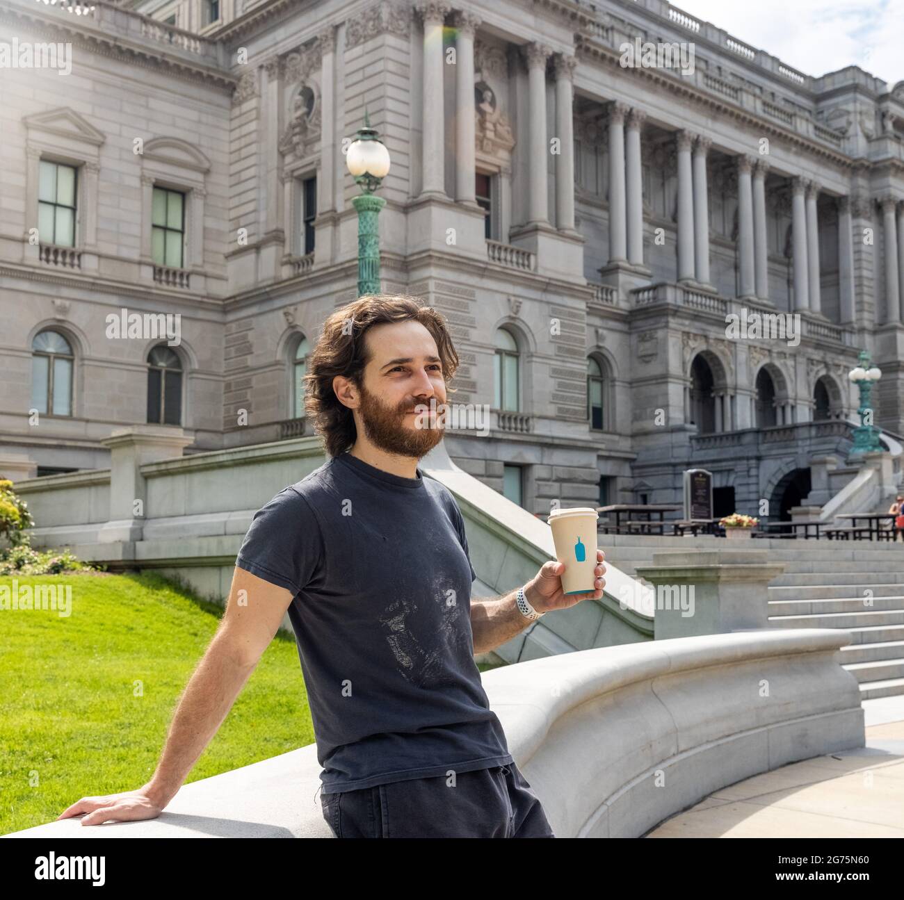 Hipster Man Drinking Blue Bottle Coffee in front of Library of Congress in Washington DC Stock Photo