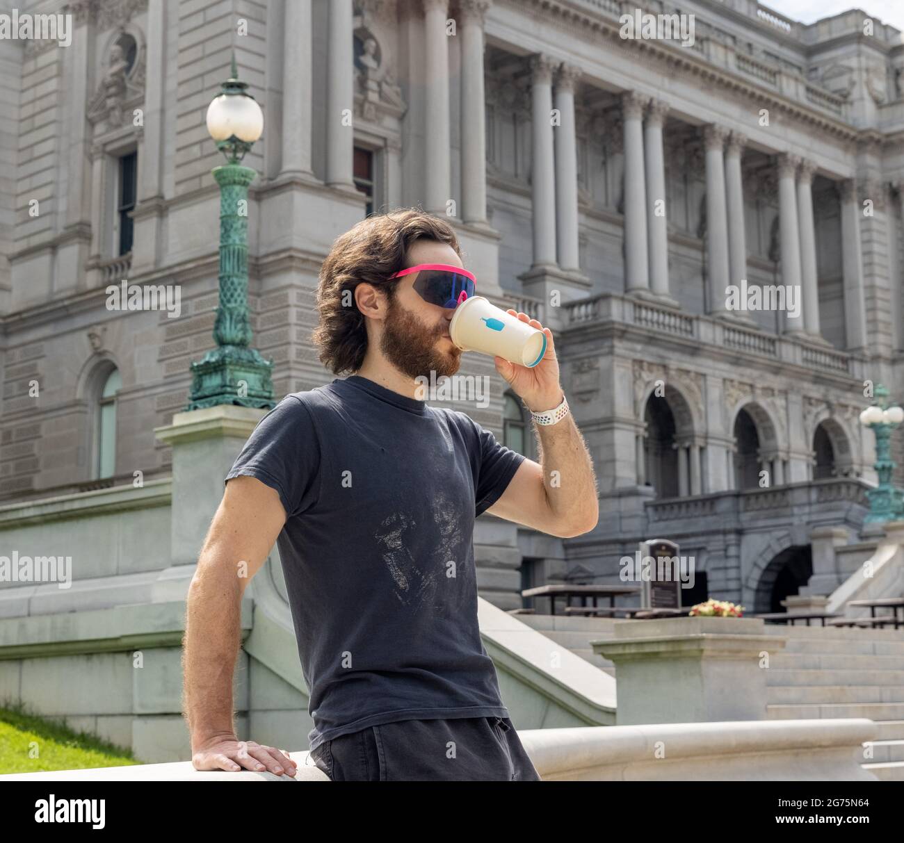 Hipster Man Drinking Blue Bottle Coffee in front of Library of Congress in Washington DC Stock Photo